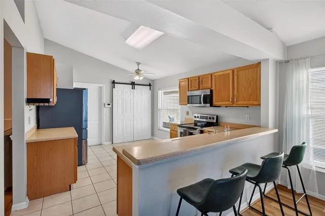 a kitchen with stainless steel appliances a sink a stove a refrigerator cabinets and a dining table with wooden floor
