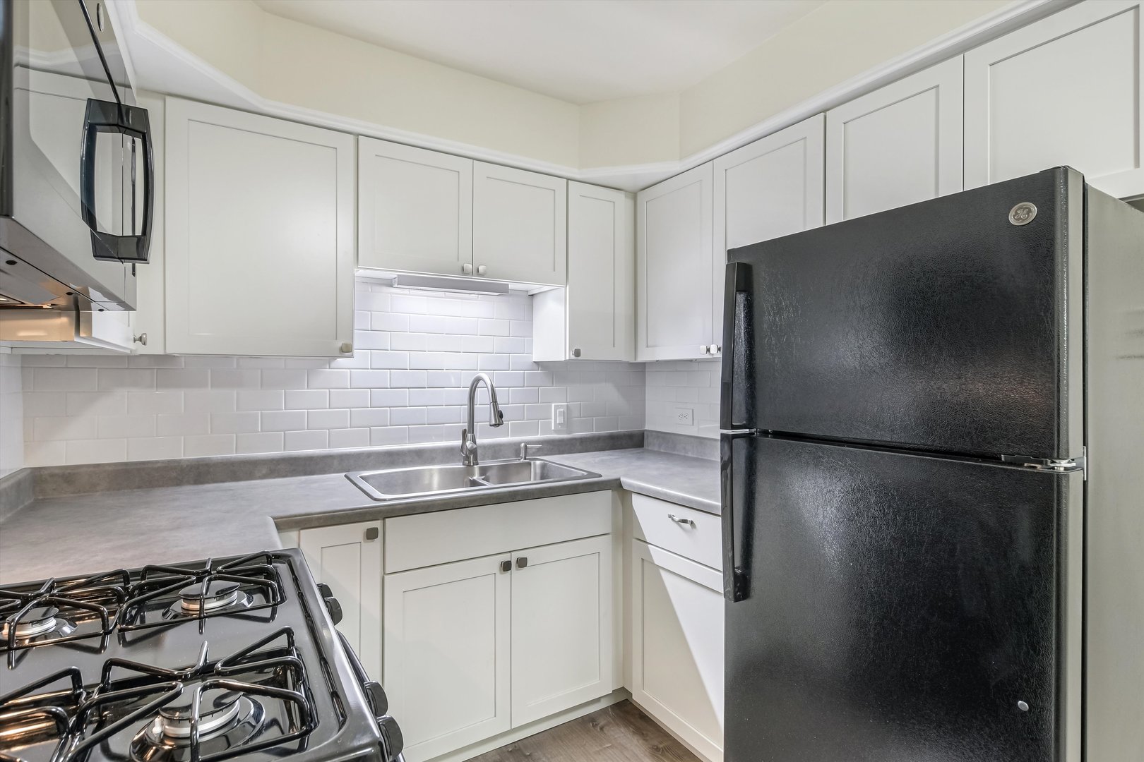 1039 College Avenue, Unit 2E Wheaton, IL 60187 - Photo 3 of 18 a kitchen with stainless steel appliances a refrigerator a sink and white cabinets