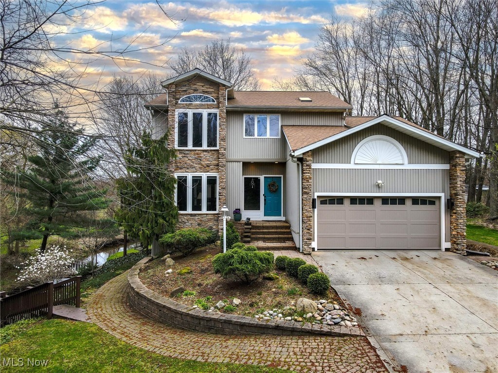2068 Chimney Ridge Drive Madison, OH 44057 - Photo 1 of 37 View of front of property with concrete driveway, stone siding, an attached garage, fence, and a shingled roof