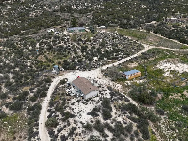 an aerial view of residential house with outdoor space and trees all around