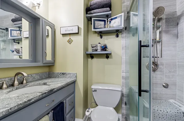 a bathroom with a granite countertop sink toilet and shower