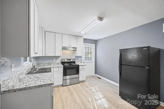 a kitchen with granite countertop a refrigerator stove and sink