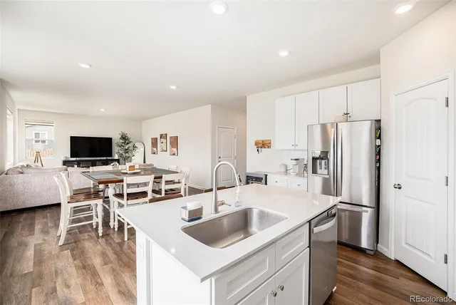 a kitchen with stainless steel appliances granite countertop a sink stove and refrigerator with wooden floor