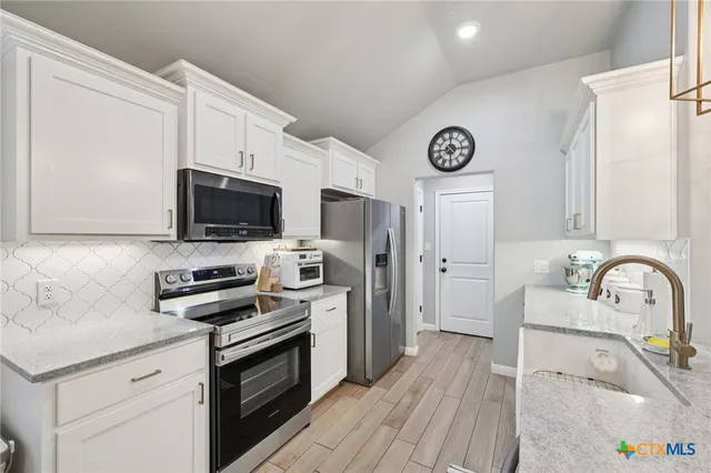 a kitchen with stainless steel appliances a stove a sink a microwave and cabinets