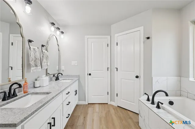a bathroom with a double vanity sink a mirror and a bathtub