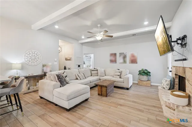 a living room with furniture a fireplace and a large mirror with wooden floor