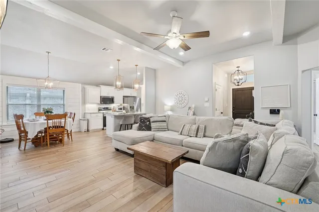 a living room with furniture kitchen view and a wooden floor