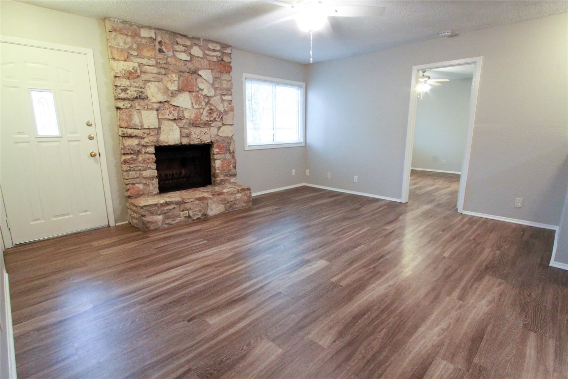 12609 Turtle Rock Road, Unit B Austin, TX 78729 - Photo 4 of 25 an empty room with wooden floor fireplace and windows