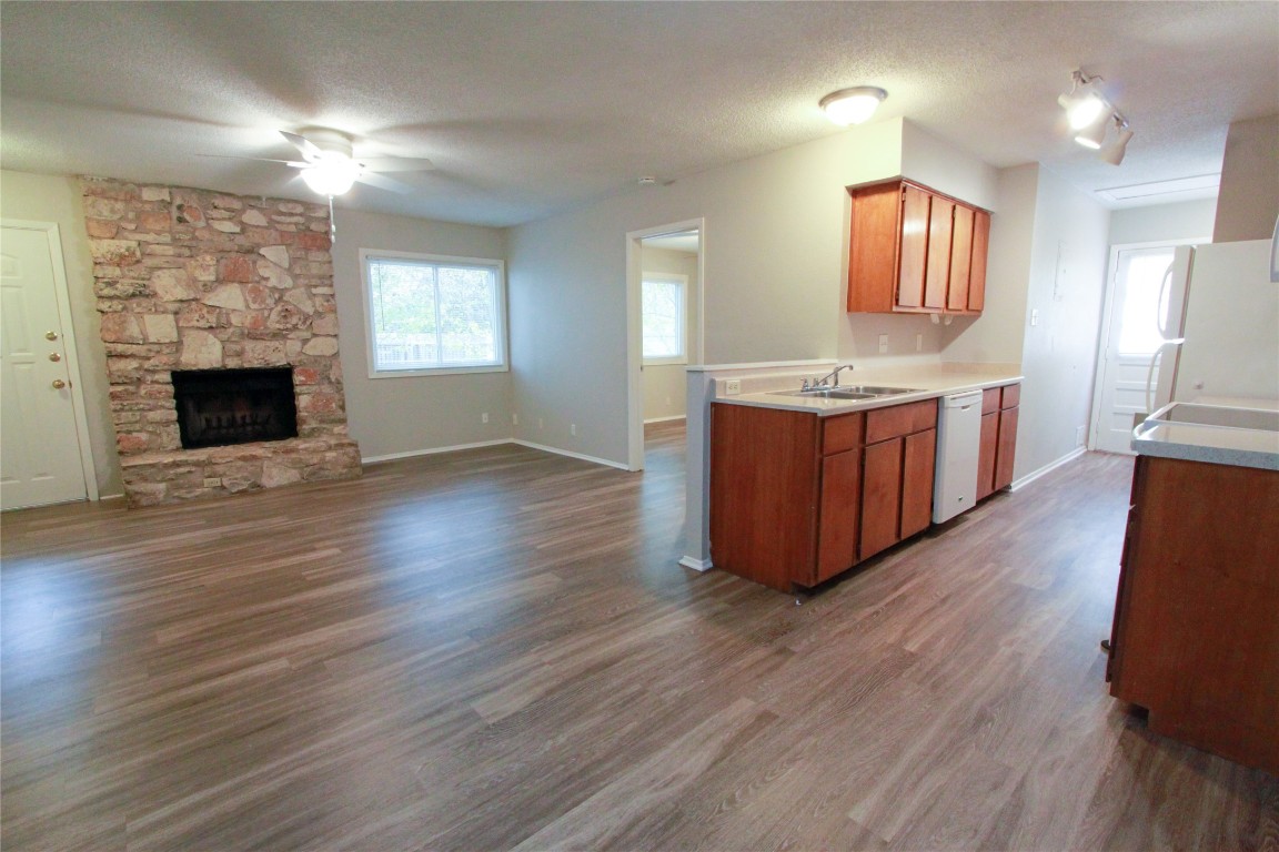 12609 Turtle Rock Road, Unit B Austin, TX 78729 - Photo 8 of 25 a large kitchen with kitchen island a sink wooden floor and a fireplace