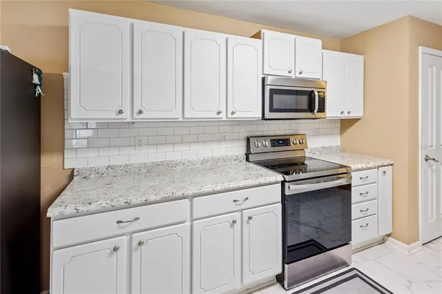 a kitchen with granite countertop white cabinets and a stove top oven