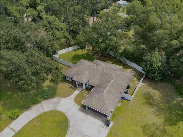 an aerial view of a house with swimming pool and large trees