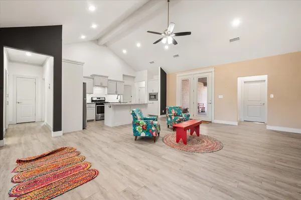 a kitchen with stainless steel appliances granite countertop a refrigerator a stove a sink and white cabinets with wooden floor