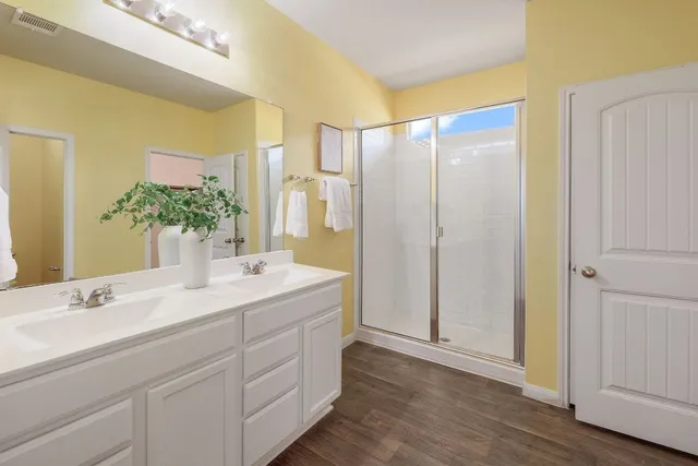 a bathroom with a double vanity sink mirror and shower