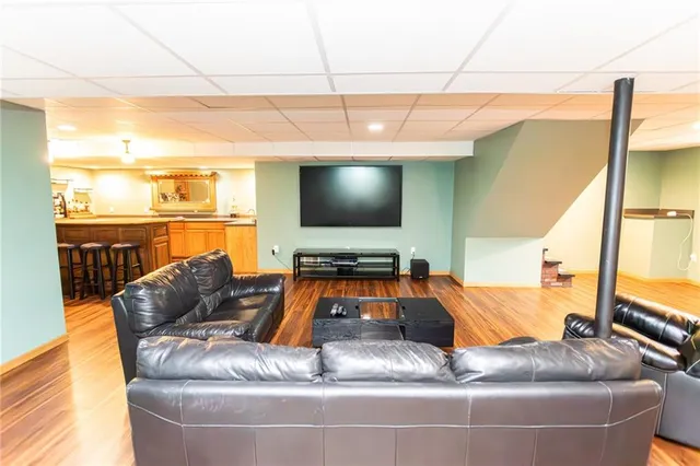 a living room with couches and kitchen view with wooden floor