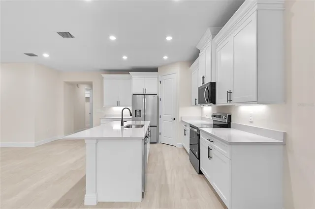 a large kitchen with stainless steel appliances lots of counter space and a sink