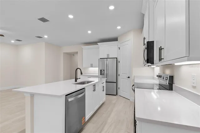 a kitchen with stainless steel appliances a refrigerator sink and white cabinets