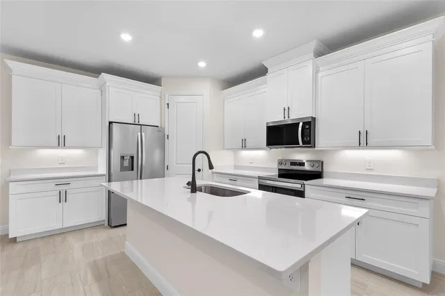 a kitchen with appliances a sink and cabinets