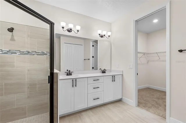 a spacious bathroom with a double vanity sink a mirror and shower