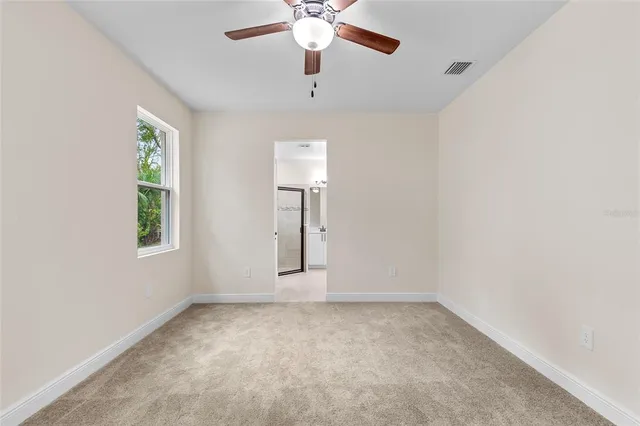 an empty room with chandelier fan and windows