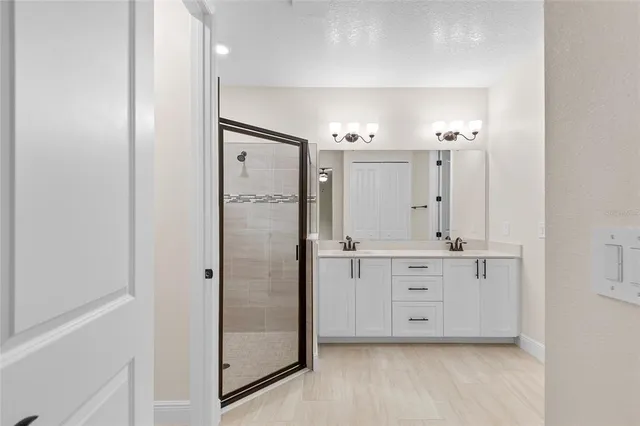 a bathroom with a double vanity sink a mirror and a shower
