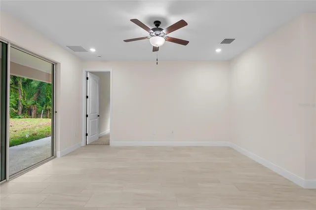 an empty room with ceiling fan and window