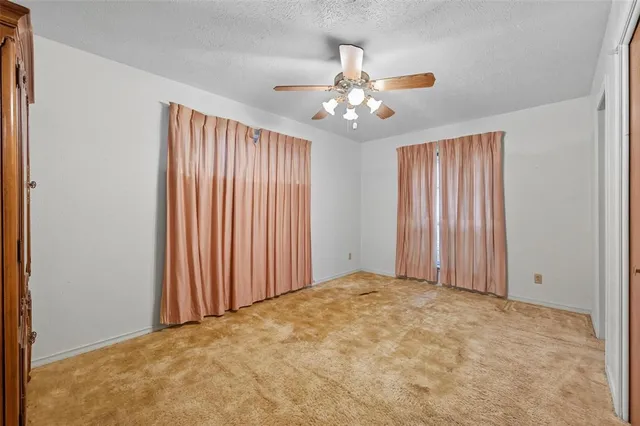 an empty room with windows and fan chandelier