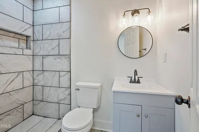a bathroom with a toilet sink vanity and mirror