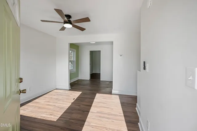 a view of a hallway with wooden floor and a ceiling fan