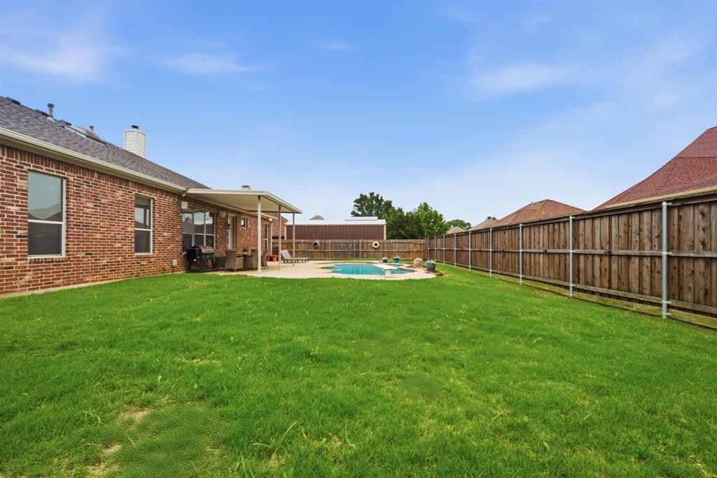 603 Cedar Drive Pilot Point, TX 76258 - Photo 33 of 39 Expansive backyard featuring a rectangular swimming pool with a surrounding concrete patio, a covered patio area, and a brick exterior home