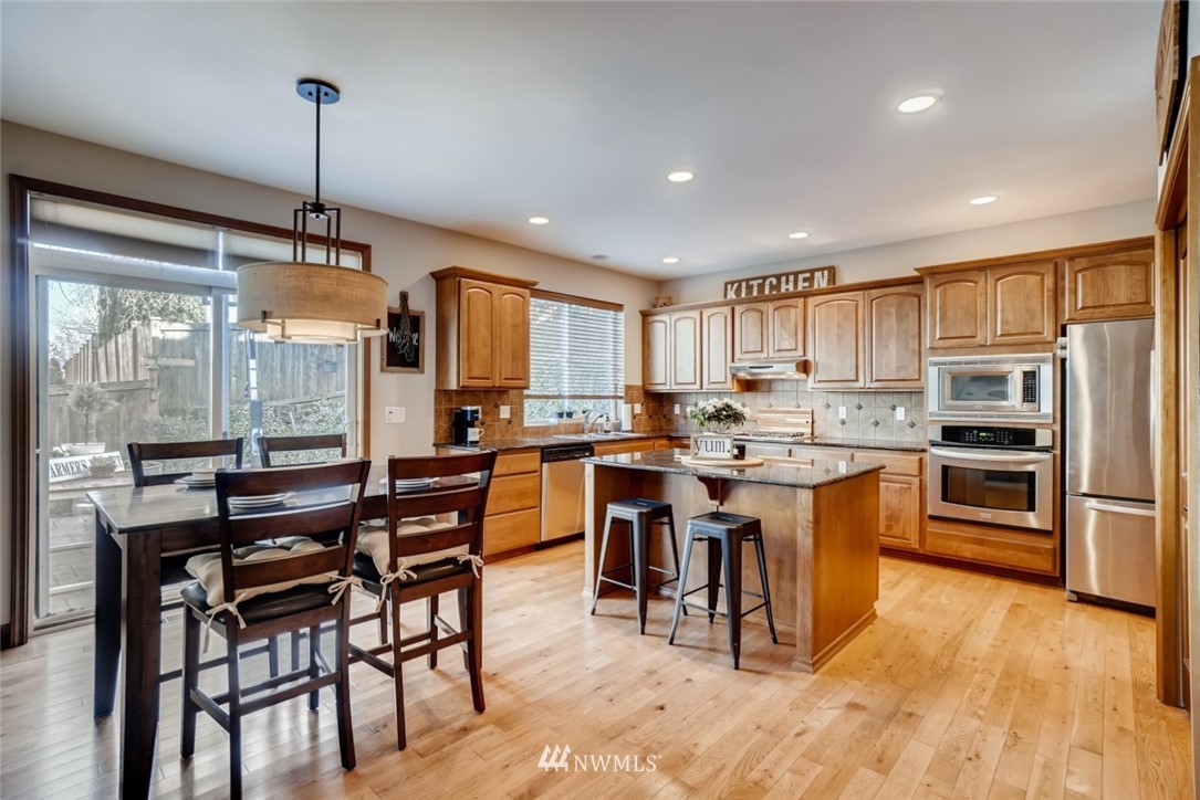 4121 223rd Place Southeast Bothell, WA 98021 - Photo 5 of 15 a kitchen with stainless steel appliances granite countertop a stove top oven a refrigerator a sink and a dining table with wooden floor