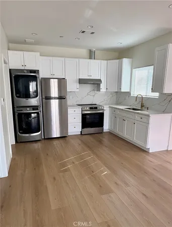 a kitchen with stainless steel appliances granite countertop a stove top oven a refrigerator and white cabinets