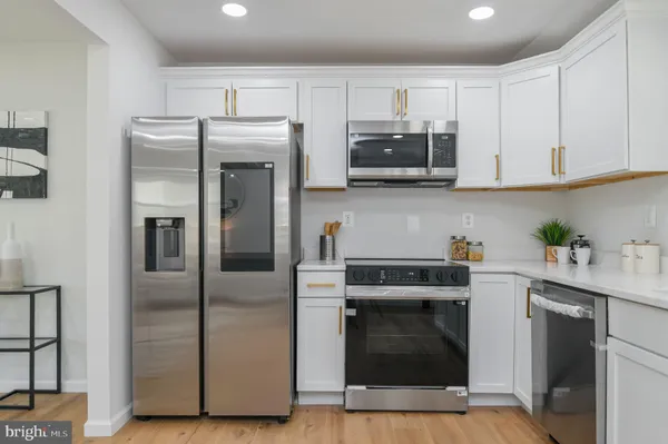 a kitchen with granite countertop a refrigerator stove and white cabinets