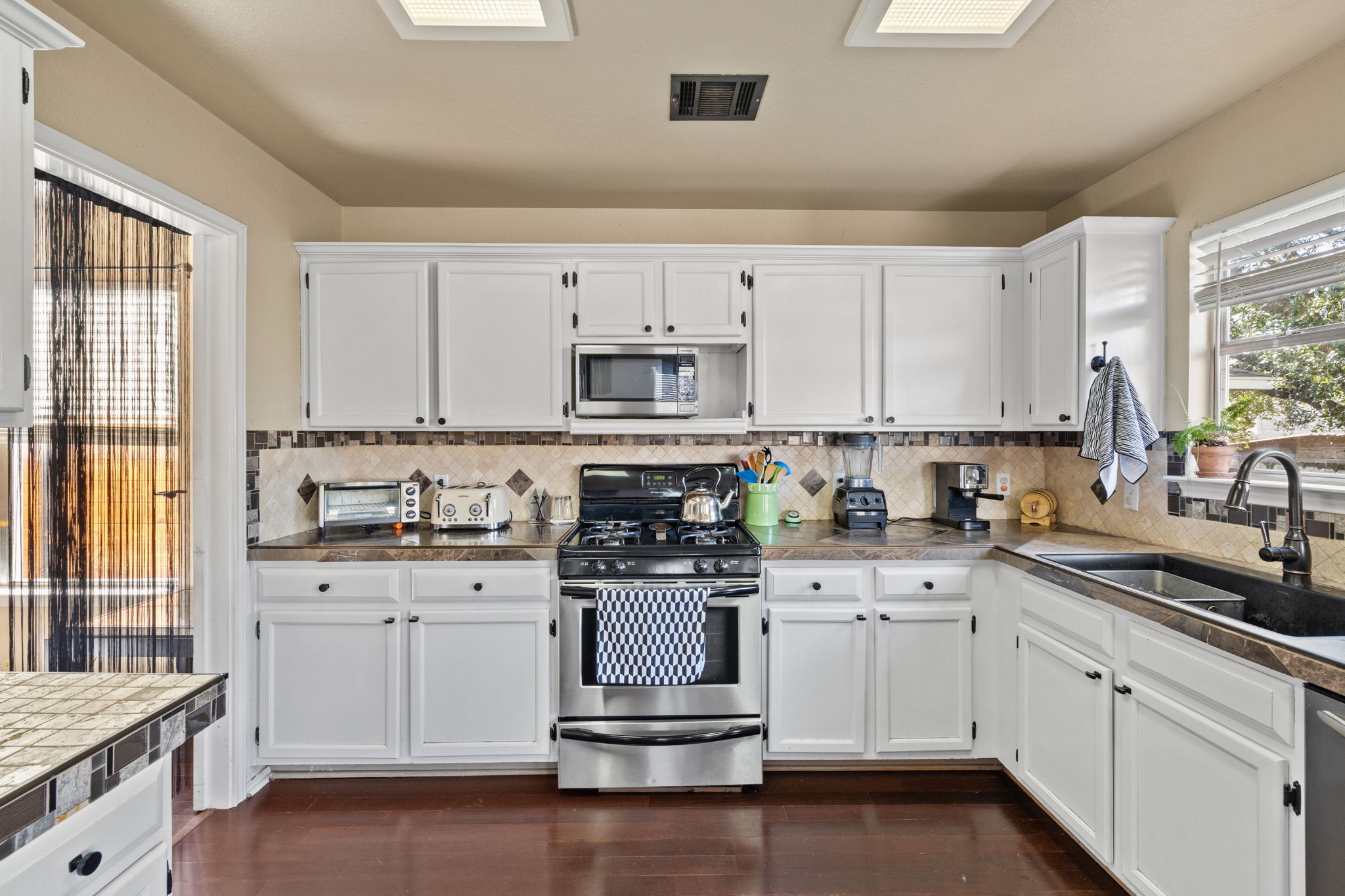 17536 Bishopsgate Drive Pflugerville, TX 78660 - Photo 12 of 28 Kitchen featuring stainless steel appliances, white cabinets, and dark wood-style flooring
