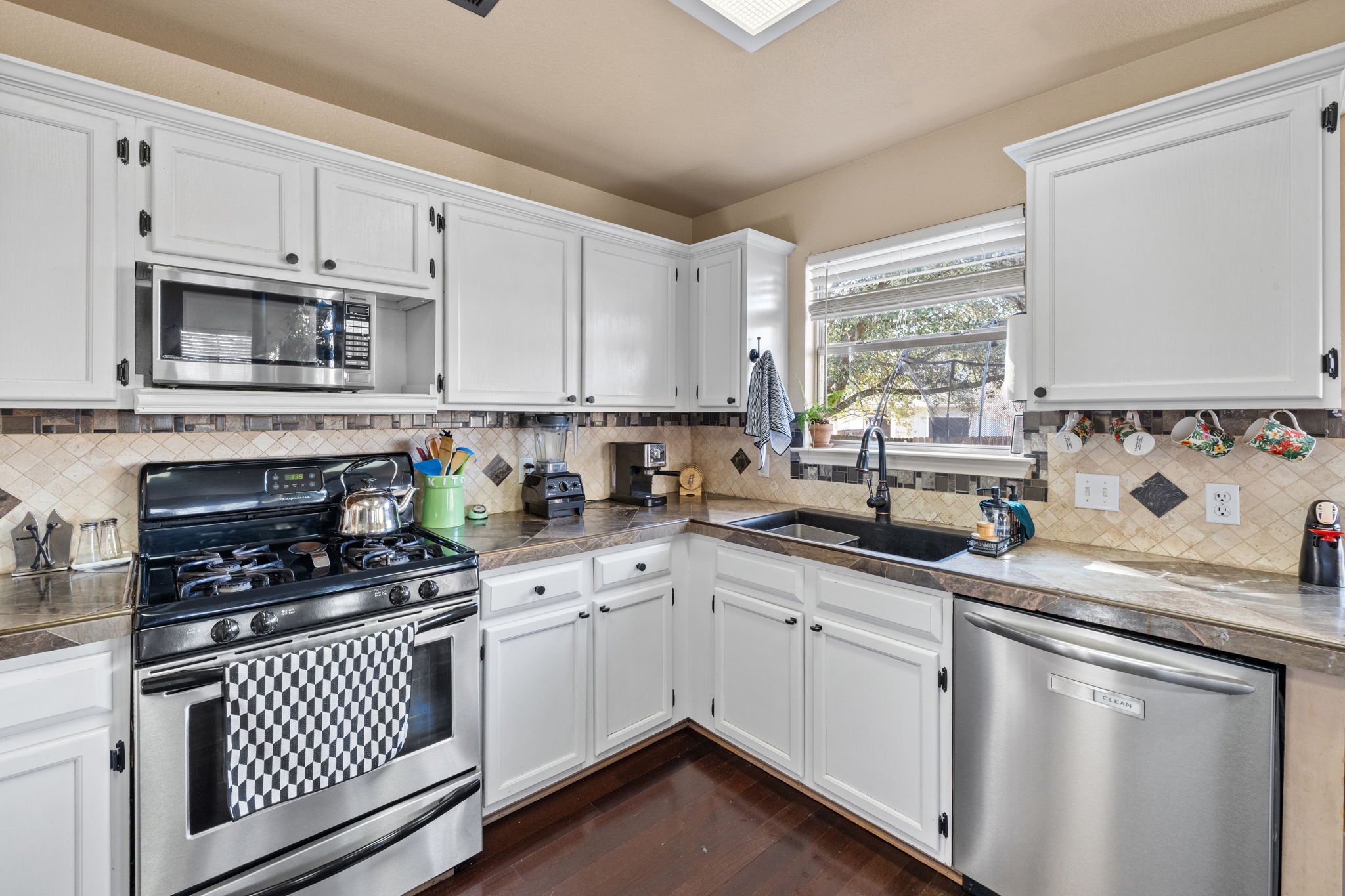 17536 Bishopsgate Drive Pflugerville, TX 78660 - Photo 13 of 28 Kitchen with stainless steel appliances, tile counters, and white cabinets