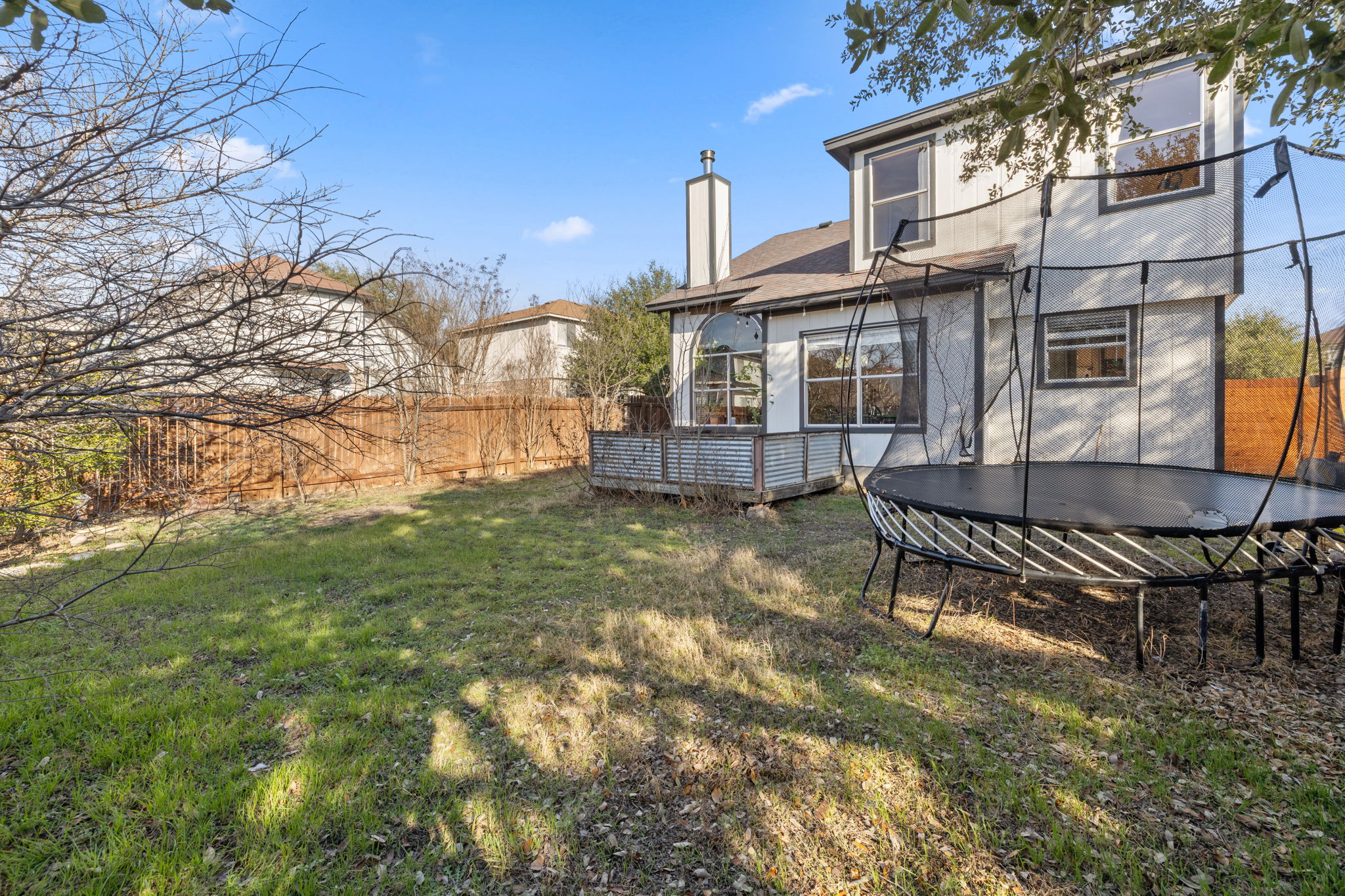 17536 Bishopsgate Drive Pflugerville, TX 78660 - Photo 26 of 28 Back of property with a deck, a fenced backyard, a trampoline, and a chimney