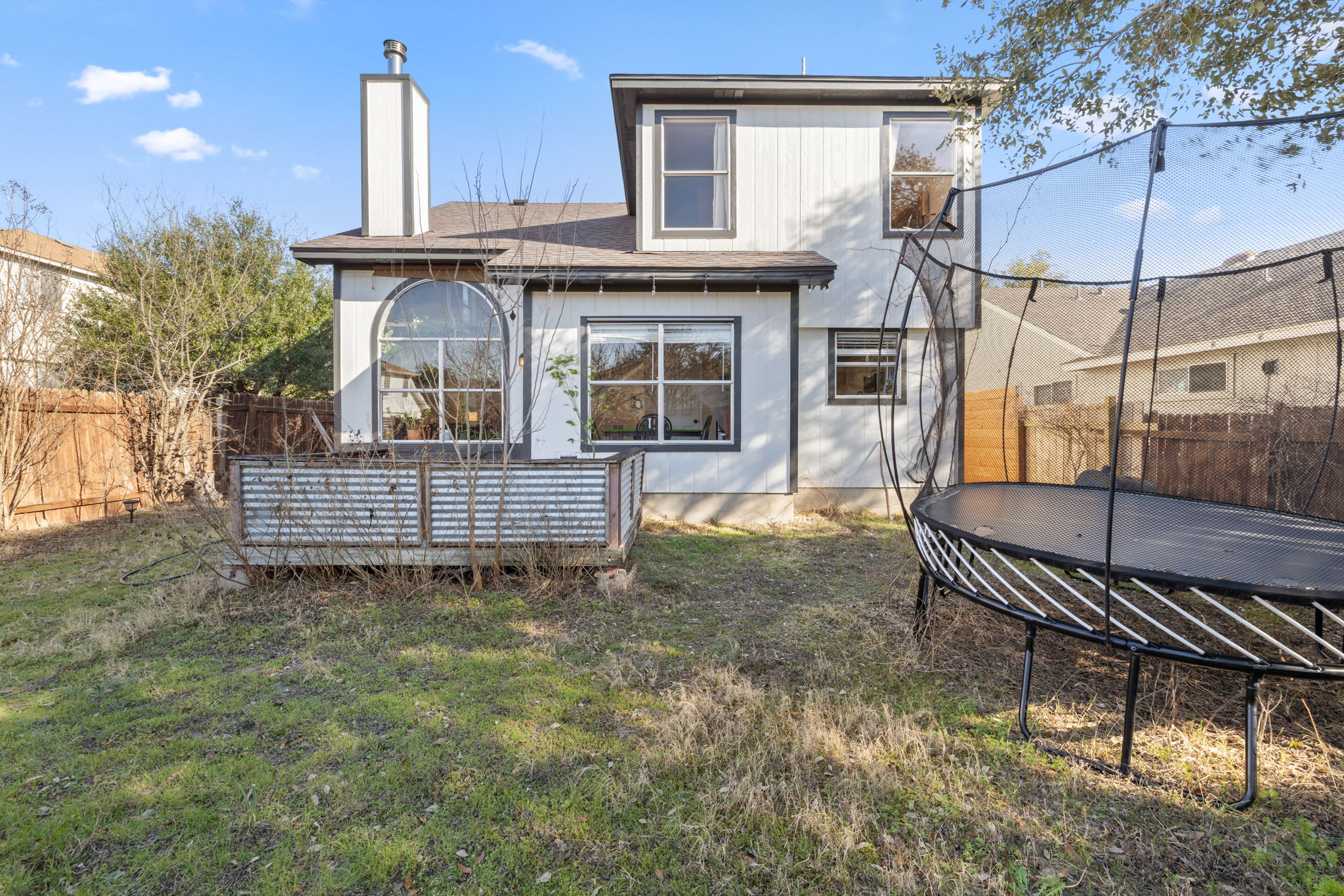17536 Bishopsgate Drive Pflugerville, TX 78660 - Photo 27 of 28 Back of property with a fenced backyard, a deck, a trampoline, and a chimney