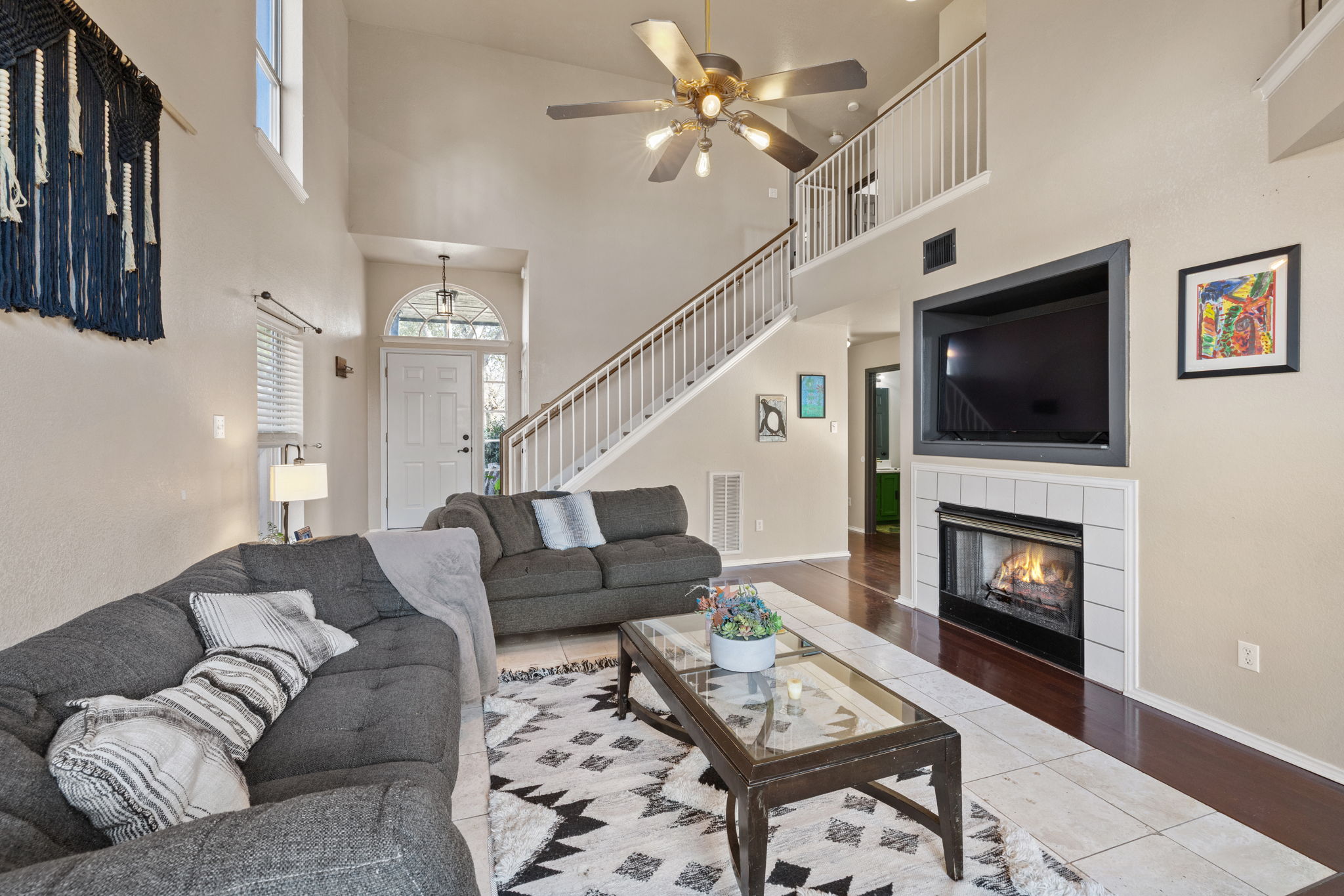 17536 Bishopsgate Drive Pflugerville, TX 78660 - Photo 6 of 35 Living room with a tile fireplace, a ceiling fan, wood finished floors, and a high ceiling