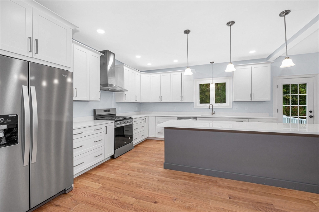 15 Norris Road Tyngsborough, MA 01879 - Photo 13 of 42 a kitchen with stainless steel appliances granite countertop a sink a stove a refrigerator and island with wooden floor