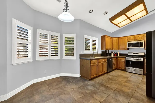 a kitchen with stainless steel appliances granite countertop a refrigerator and a window