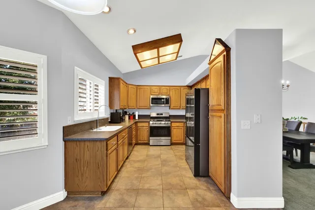 a kitchen with stainless steel appliances granite countertop a sink a stove and a window