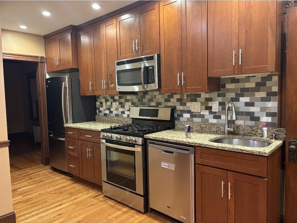 121-123 Willow Street, Unit 2 Boston, MA 02132 - Photo 3 of 8 a kitchen with stainless steel appliances granite countertop a sink stove and refrigerator