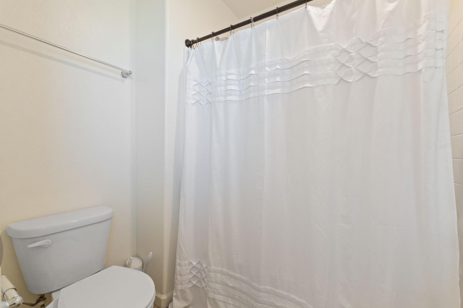 802 Riesling Lane Coalinga, CA 93210 - Photo 21 of 68 a white toilet sitting next to a shower curtain
