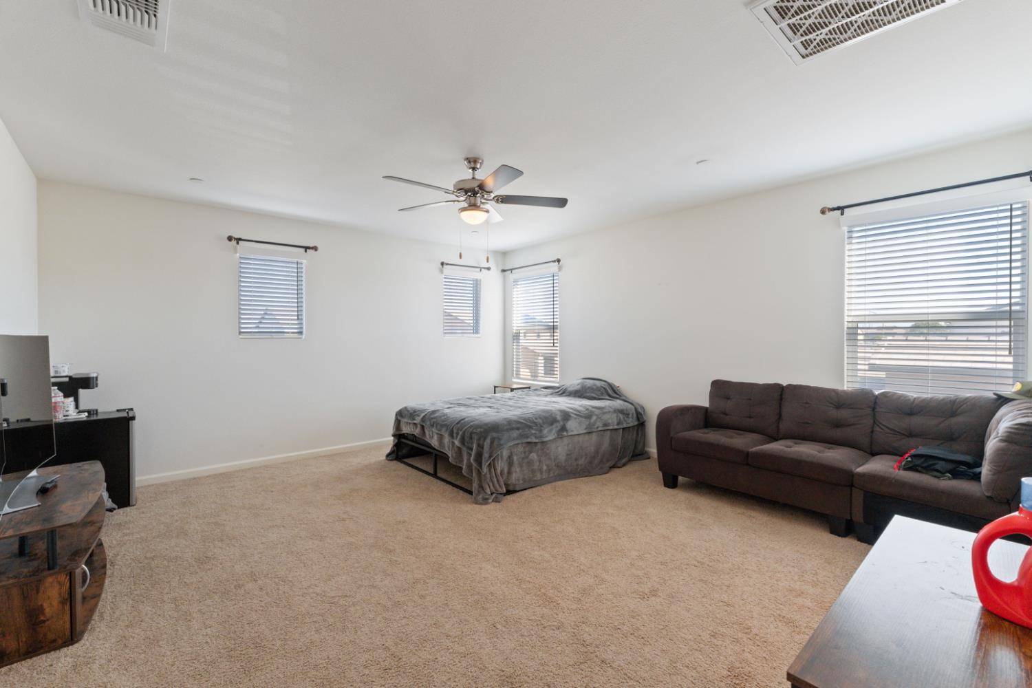 802 Riesling Lane Coalinga, CA 93210 - Photo 32 of 68 a spacious bedroom with a bed a couch and a window