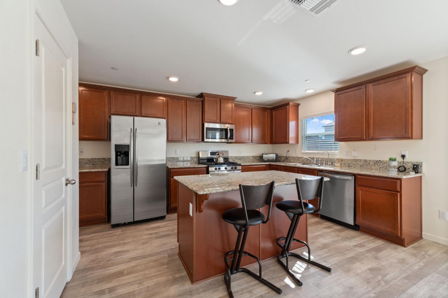 802 Riesling Lane Coalinga, CA 93210 - Photo 4 of 68 a kitchen with a refrigerator a sink dishwasher with a dining table and chairs