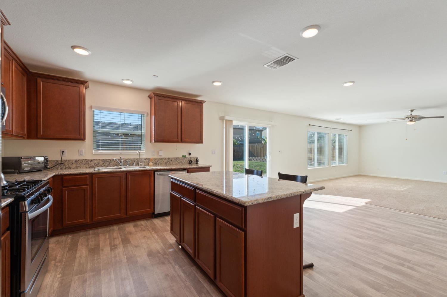802 Riesling Lane Coalinga, CA 93210 - Photo 6 of 68 a kitchen with kitchen island granite countertop a sink stove and wooden cabinets