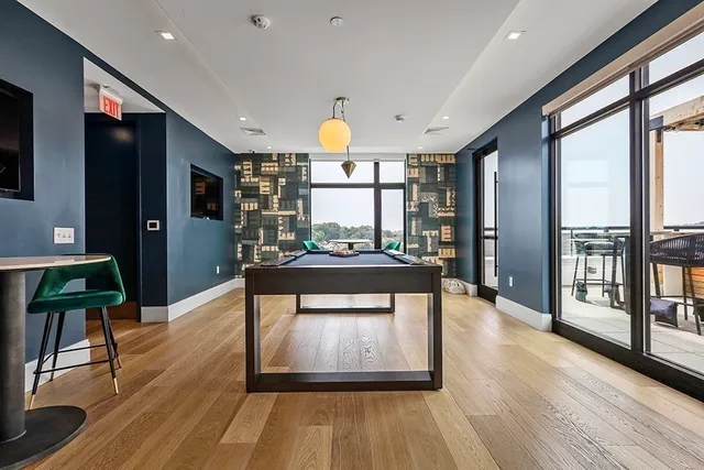 a living room with stainless steel appliances granite countertop a refrigerator a stove top oven and a dining table with wooden floor