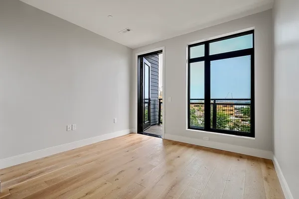 a view of an empty room with a window and wooden floor