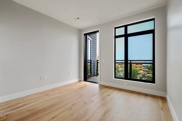 a view of an empty room with a window and wooden floor