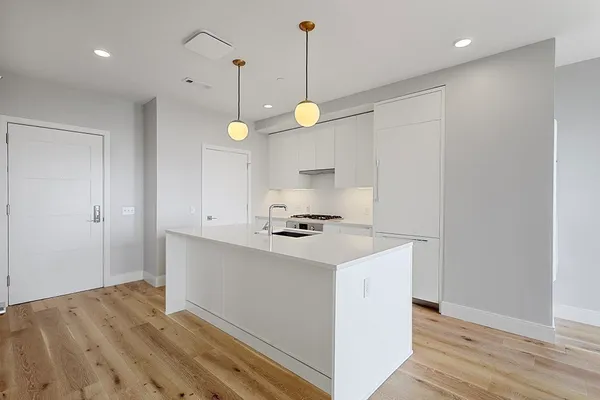 a kitchen that has a sink a stove and wooden floor