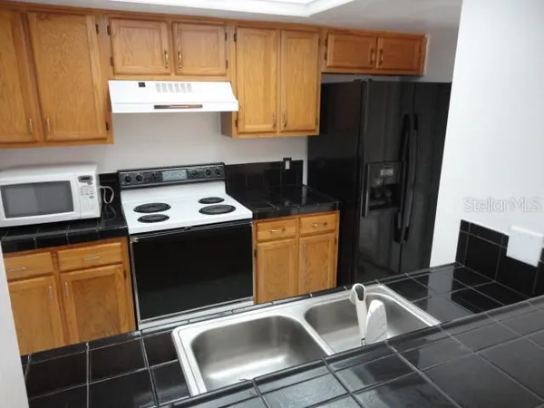 a kitchen with granite countertop a stove refrigerator and microwave